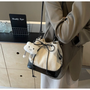 Detail of canvas bucket bag with leather trim, drawstring bow and plush cloud charm