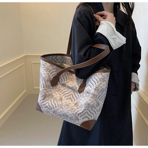 Detail view of large tote bag with retro wave patterns and brown leather reinforcement