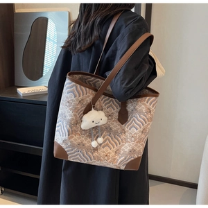 Détail du sac cabas à motifs de vagues avec poignées en cuir et breloque nuage en peluche
