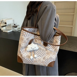 Détail d'un grand sac cabas en jacquard à motifs ondulés avec un charm nuage mignon
