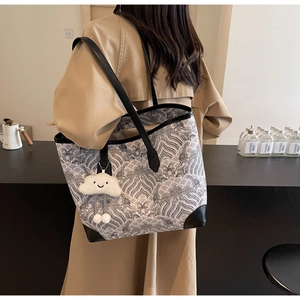 Détail d'un grand sac cabas avec motifs ondulés, anses en cuir et breloque nuage doux