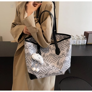 Détail du sac cabas imprimé avec motif de vagues et breloque en peluche nuage blanc