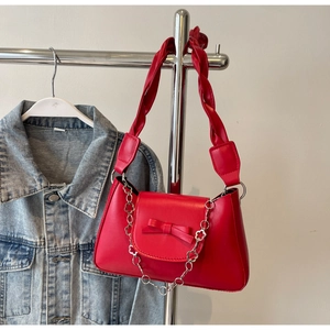 Detail of red faux leather handbag with bow decoration and thick braided shoulder strap