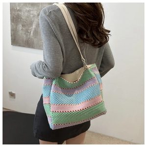 Détail d'un sac cabas tissé à rayures colorées avec bandoulière en cuir crème