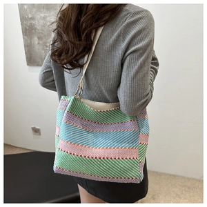 Détail du sac cabas tissé à rayures colorées avec bandoulière en cuir blanc sur l'épaule