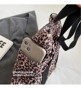 Detail of leopard print tote bag with functional outer pocket holding a phone