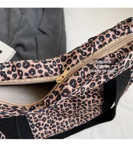 Close-up of smooth gold zipper and black strap on a leopard print tote bag