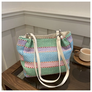 Détail du sac à bandoulière tissé coloré avec motif rayé et lanières en cuir blanc