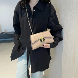 Sac bandoulière beige minimaliste avec fermoir en T doré porté par un mannequin
