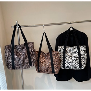 Large leopard print canvas tote bags in three colors hanging on a minimal display