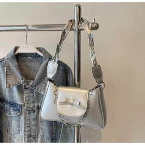 Detail of silver metallic handbag with bow accent and decorative flower chain