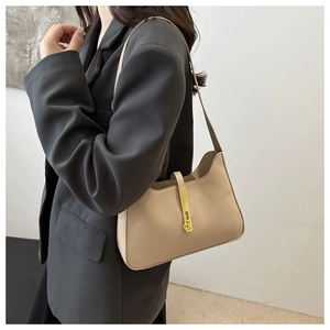 Sac baguette beige en similicuir avec un fermoir rectangulaire doré porté à l'épaule