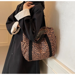 Detail of leopard print canvas tote bag featuring side pockets and black shoulder straps