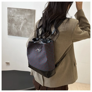 Close-up of canvas backpack with red polka dots and silver metal bow detail