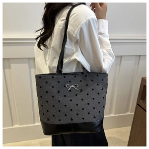 Close-up of a polka dot canvas bucket bag with bow embroidery and silver metal hardware