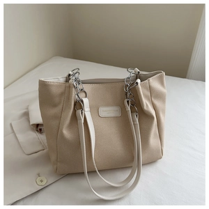 Dettaglio della borsa tote in tela beige con tracolla in pelle e catena in metallo