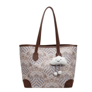 Fashion tote bag with vintage wave pattern, brown leather handles, and cloud charm decoration
