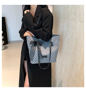 Détail d'un sac cabas gris à pois avec un grand nœud en dentelle noire et cœurs