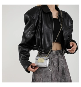 Gros plan sur le mini sac métallisé argenté avec chaîne dorée et boucle sur veste en cuir