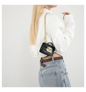 Gros plan d'un mini sac à chaîne noir avec fermoir doré sur la tenue d'un mannequin