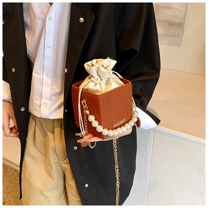Dettaglio di una borsa a secchiello marrone con manico di perle e catena