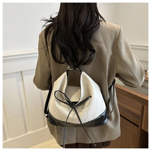 Minimalist herringbone canvas backpack with black leather trim and bow drawstring detail