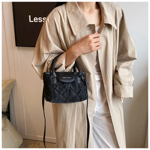 Close-up of black quilted bucket bag featuring a fashion logo and elegant chain strap
