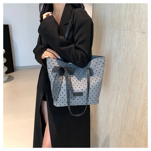 Sac fourre-tout gris à motif cœurs noirs et nœud en dentelle porté à l'épaule