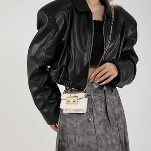 Mini sac bandoulière chic avec chaîne dorée porté sur une veste noire