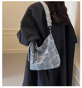 Detail of blue and white woven tote bag showing adjustable plaid strap and metal hardware