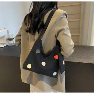 Detail of black canvas tote with colorful heart patches and a matching mini pouch charm