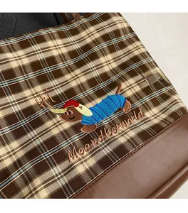 Close-up of vintage plaid tote bag with exquisite dachshund embroidery and leather trim