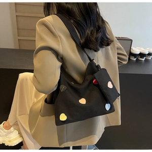 Detail of black canvas tote bag with colorful heart patches and small hanging pouch