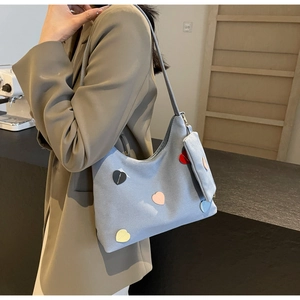 Detail of grey canvas tote bag with multi-colored heart patches and small detachable pouch