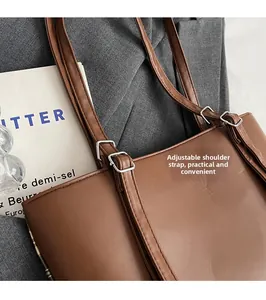 Detail of dark brown leather tote with adjustable metal buckle on shoulder strap