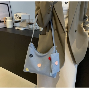 Detail of light blue canvas hobo bag featuring colorful heart patches and mini purse