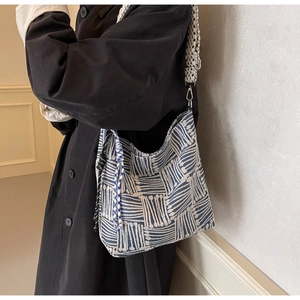 Detail of blue and white woven tote bag with a multi-color braided shoulder strap