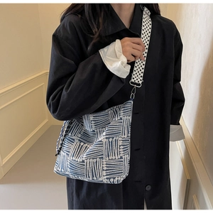 Detail of blue striped canvas tote bag with houndstud strap worn by a female model