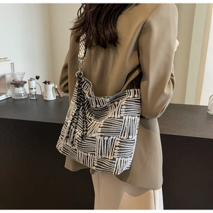 Detail of a large striped canvas tote bag with a geometric pattern strap and black tassel