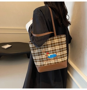 Detail of dachshund embroidery on brown checkered canvas tote bag with leather straps