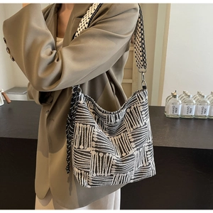 Detailed close-up of woven geometric stripe texture and black tassel on hobo bag