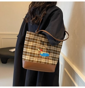 Detail view of brown checkered tote bag with embroidered dachshund and leather bottom
