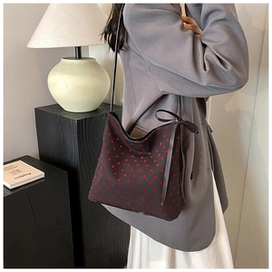 Detailed shot of fabric shoulder bag with red heart pattern and side ribbon bow detail