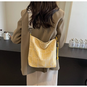 Detail of a large yellow striped canvas tote bag with a checkered jacquard strap