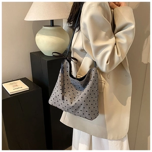 Close-up of grey polka dot bucket bag with black hearts and a brown silk ribbon bow