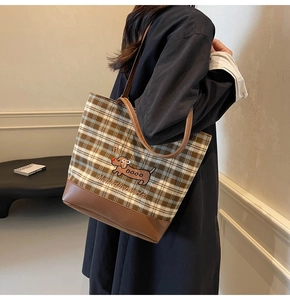 Detail of checkered tote bag with dachshund embroidery and brown leather trimming