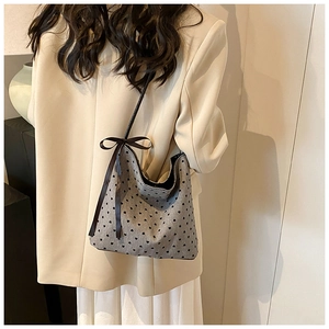 Polka dot shoulder bag with heart pattern and black ribbon bow detail on woman