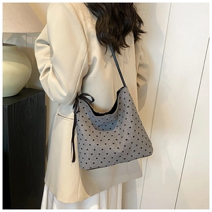 Detail of grey bucket bag with heart pattern and black ribbon bow on white blazer