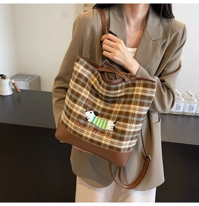 Close-up of brown plaid tote bag with detailed dog embroidery and leather base