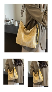 Detail of yellow striped canvas hobo bag with woven strap and decorative tassel